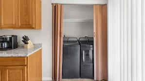Uma cozinha compacta com armários de madeira, uma cafeteira e um conjunto de facas sobre o balcão.