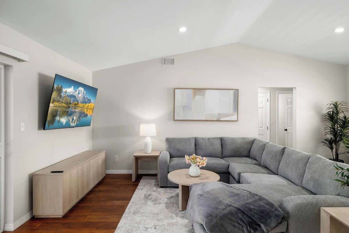 A modern living room with a grey sectional sofa, a round coffee table, and a painting on the wall.