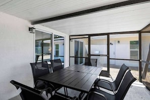 A covered outdoor patio with a table and chairs, large windows, and a view of the surrounding area. - Modern 3 Bedroom, Wesley Chapel! (Wesley Chapel)