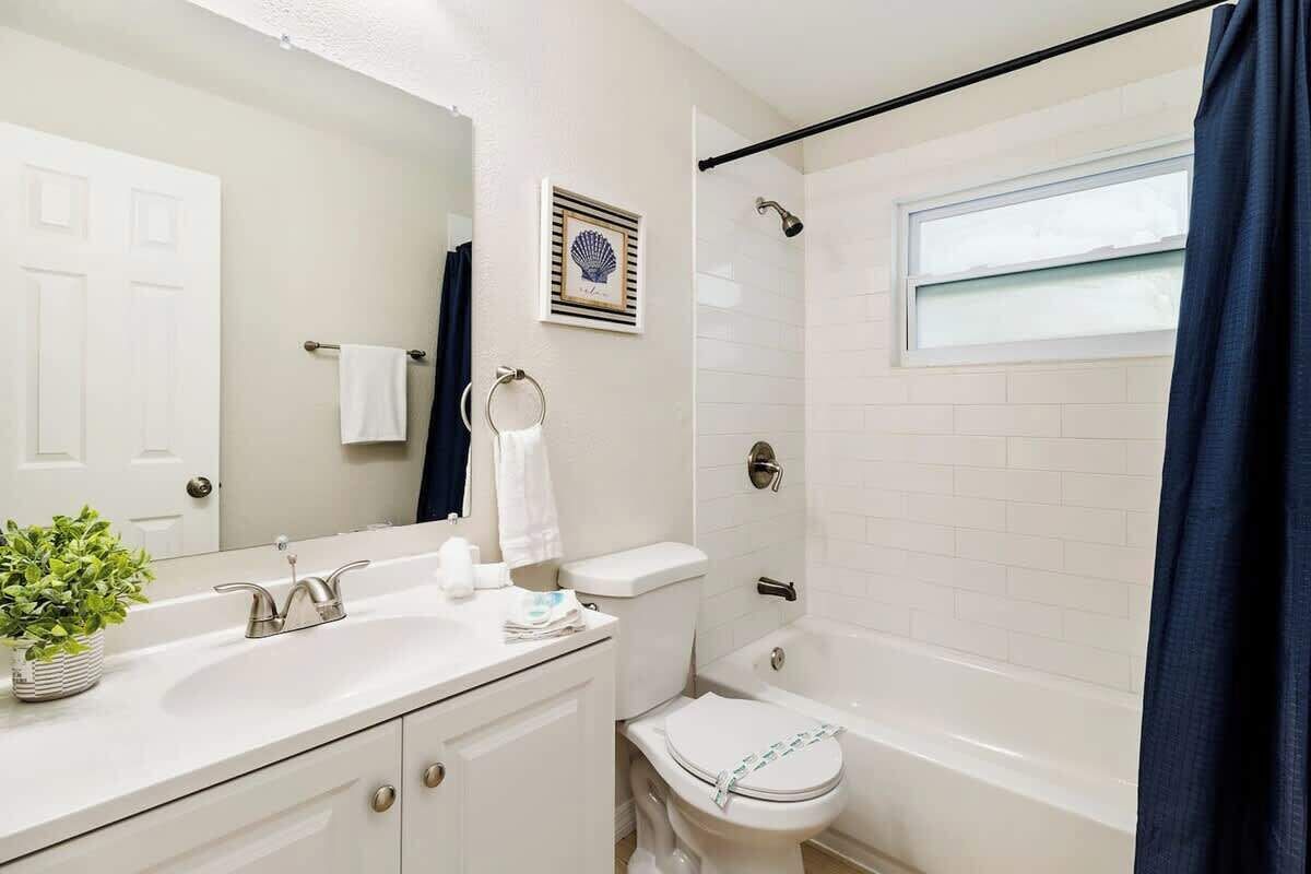 A bathroom with a white sink, a toilet, a bathtub, and a shower curtain.