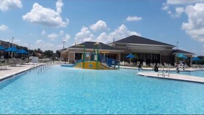 Ein Swimmingpool mit Wasserrutsche, Liegestühlen und Sonnenschirmen.