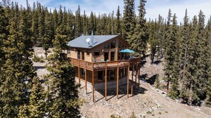 Eine Holzhütte mit einer Terrasse, umgeben von dichtem Wald.