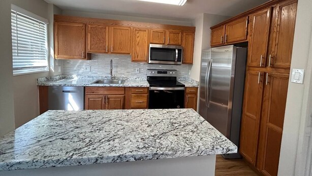 A kitchen with wooden cabinets, a stainless steel refrigerator, a microwave, and a granite countertop. - 3-bedroom townhome Summer Rental in fabulous Hyattsville with WiFi, AC (Hyattsville)