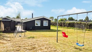 A residential area with a house, a swing set, and a fenced play area.