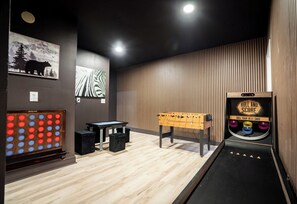 A room with a foosball table, a foosball table with a scoreboard, and a foosball table with a scoreboard.