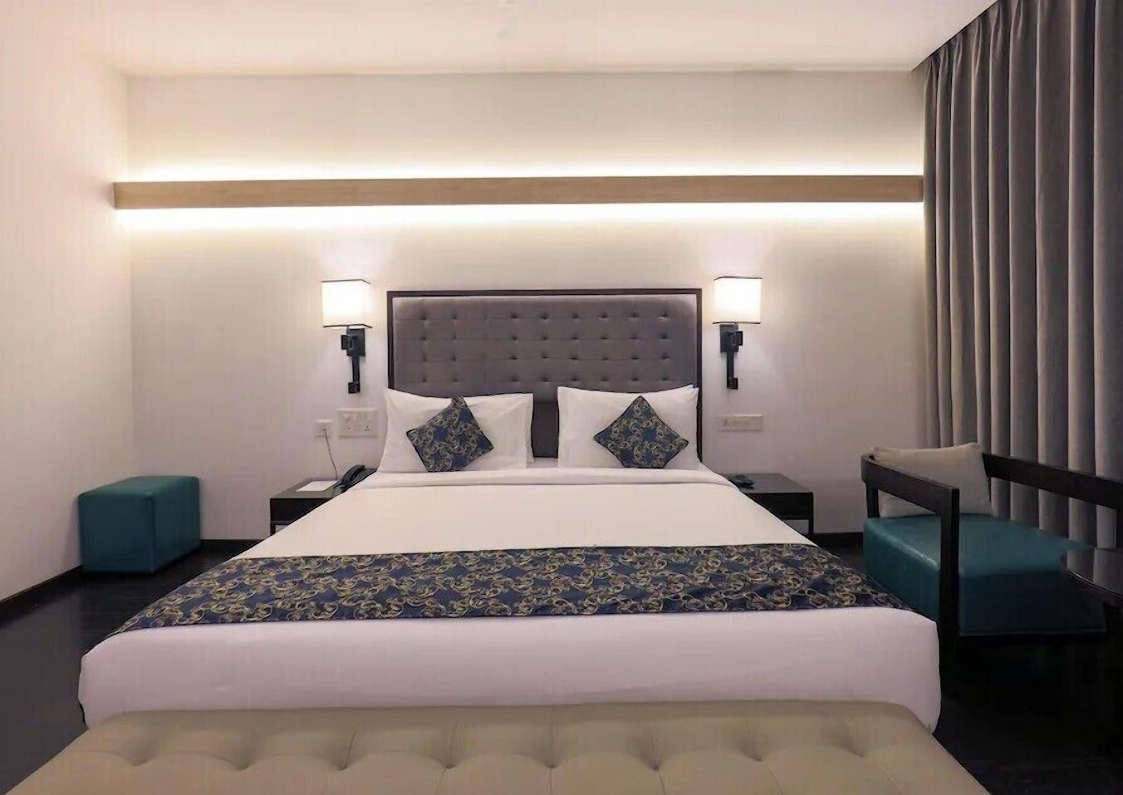 A hotel room with a large bed, two bedside tables, a chair, and a desk.