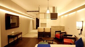 A hotel room with a bed, a desk, two chairs, a sofa, and a TV. - Hotel Deccan Serai Grande (Hyderabad)