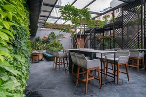An outdoor patio with a table and chairs, surrounded by greenery and a metal fence. - Hotel Deccan Serai Grande (Hyderabad)