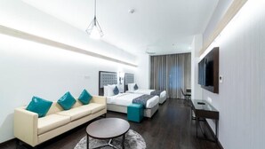 A modern hotel room with a sofa, two beds, a TV, and a desk. - Hotel Deccan Serai Grande (Hyderabad)