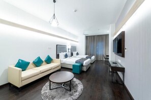 A modern hotel room with a sofa, two beds, a TV, and a desk. - Hotel Deccan Serai Grande (Hyderabad)