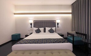 A hotel room with a large bed, two bedside tables, a chair, and a desk. - Hotel Deccan Serai Grande (Hyderabad)