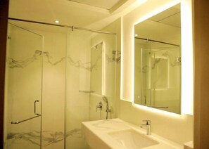 A modern bathroom with a glass-enclosed shower, a marble backsplash, and a large mirror above the sink. - Hotel Deccan Serai Grande (Hyderabad)