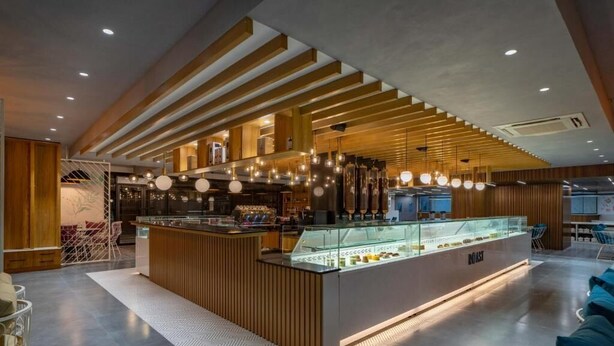 Un café moderne avec un comptoir en bois, des lampes suspendues et une vitrine.