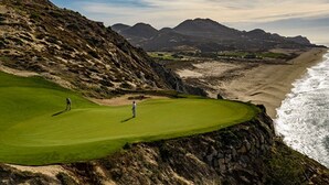 A coastal golf course with a view of the ocean and mountains.