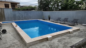 Una piscina al aire libre de temporada, sillones reclinables de piscina