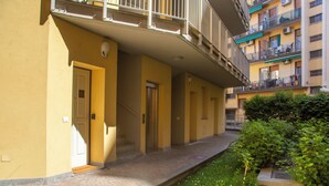 A corridor with doors, a small garden, and a balcony with railings. - Prime Living - [Apartment GOLD] on the Navigli (Milano)