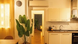 A modern kitchen with white cabinets, a wooden countertop, and a built-in oven. There is a potted plant on the left and a clock on the wall. - Prime Living - [Apartment GOLD] on the Navigli (Milano)