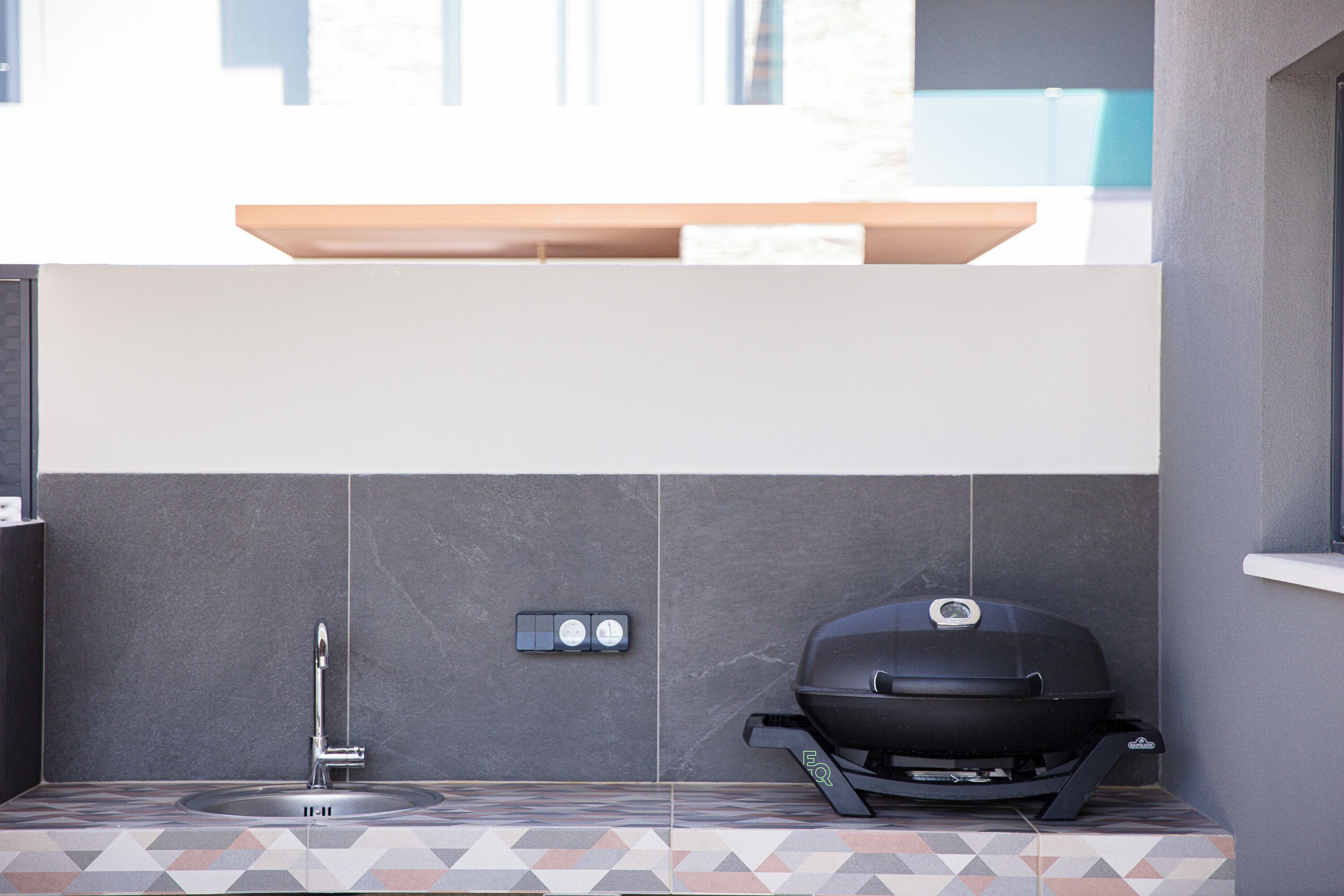 A modern outdoor kitchen with a built-in grill, a sink, and a countertop.