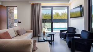 Un salon moderne comprenant un canapé, deux fauteuils, une table basse et un téléviseur fixé au mur.