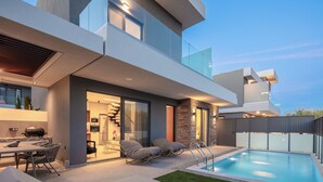 Une maison moderne dotée d’une piscine, d’un espace salon extérieur et d’un escalier menant à un étage supérieur.