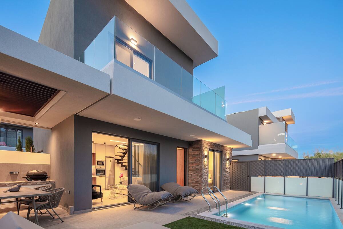 A modern house with a swimming pool, outdoor seating, and a staircase leading to an upper level.