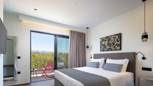 Une chambre d’hôtel moderne avec un grand lit, une porte-fenêtre coulissante donnant sur un balcon, un fauteuil rouge et une vue sur la ville.