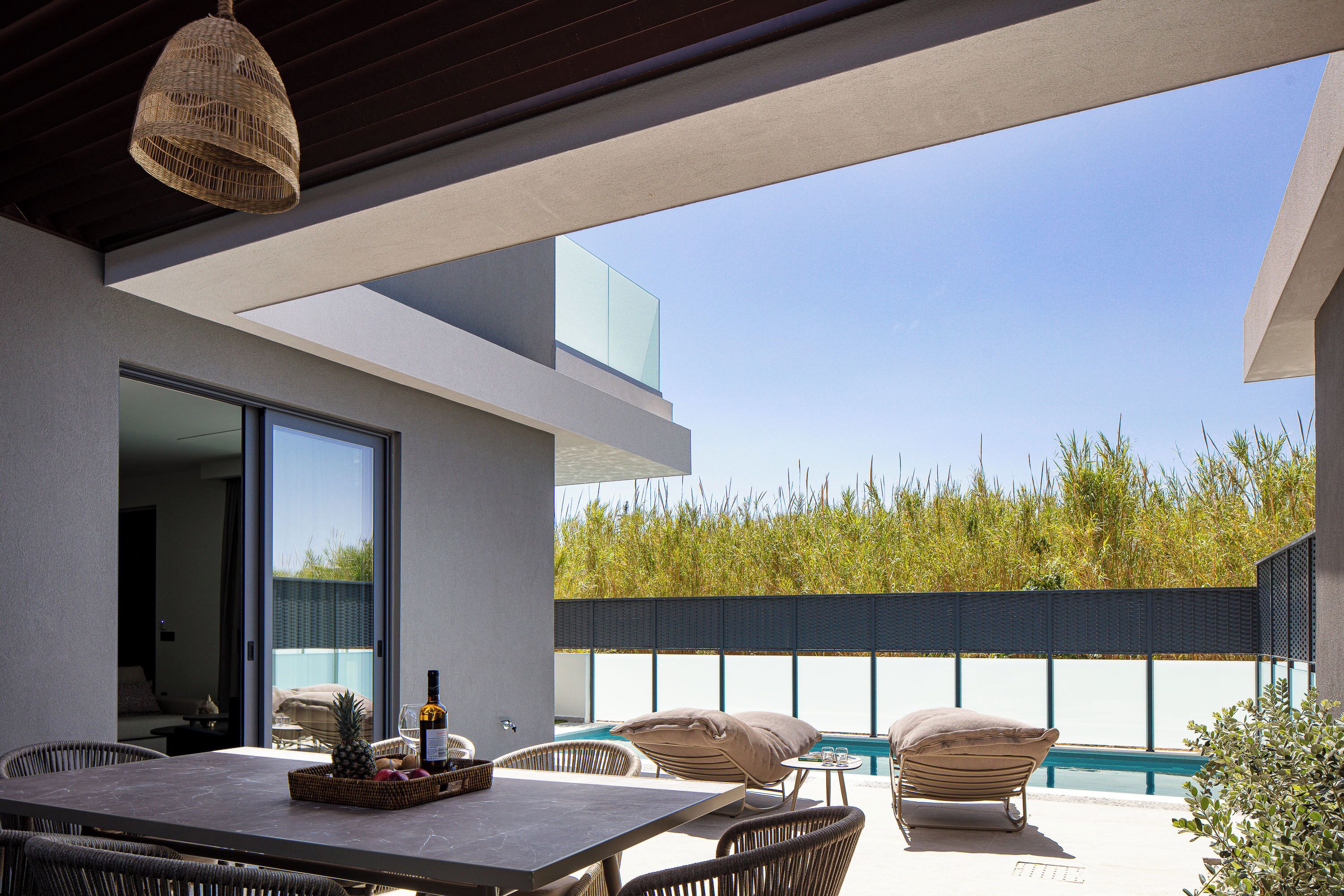 Un patio al aire libre con una mesa de comedor, sillas de mimbre y una piscina.