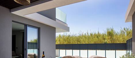 Un patio al aire libre con una mesa de comedor, sillas de mimbre y una piscina.