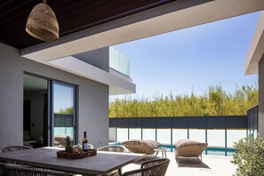 Una piscina al aire libre, sombrillas, sillones reclinables de piscina