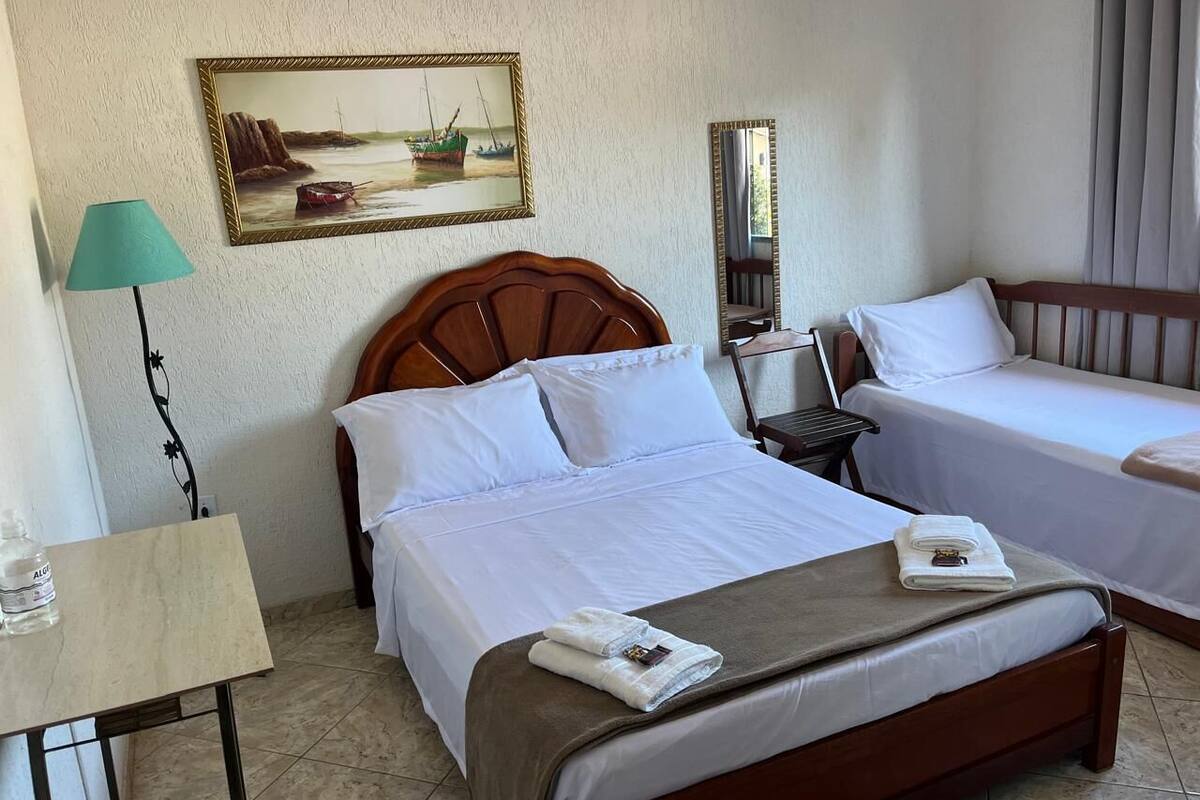 Ett hotellrum med två sängar, ett skrivbord, en lampa, en tavla och en spegel.