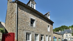 Un bâtiment en pierre doté de nombreuses fenêtres et d’un portail rouge.