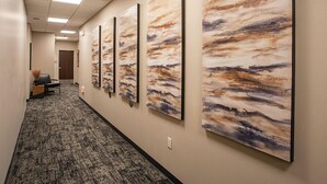 A hallway with a carpeted floor, a chair, and a door at the end. - The Intrepid (Duluth)