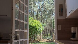 Een open deur die uitkomt op een houten terras met uitzicht op een bos.