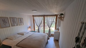 Een slaapkamer met een groot bed, een nachtkastje, een bureau en een raam met gordijnen.