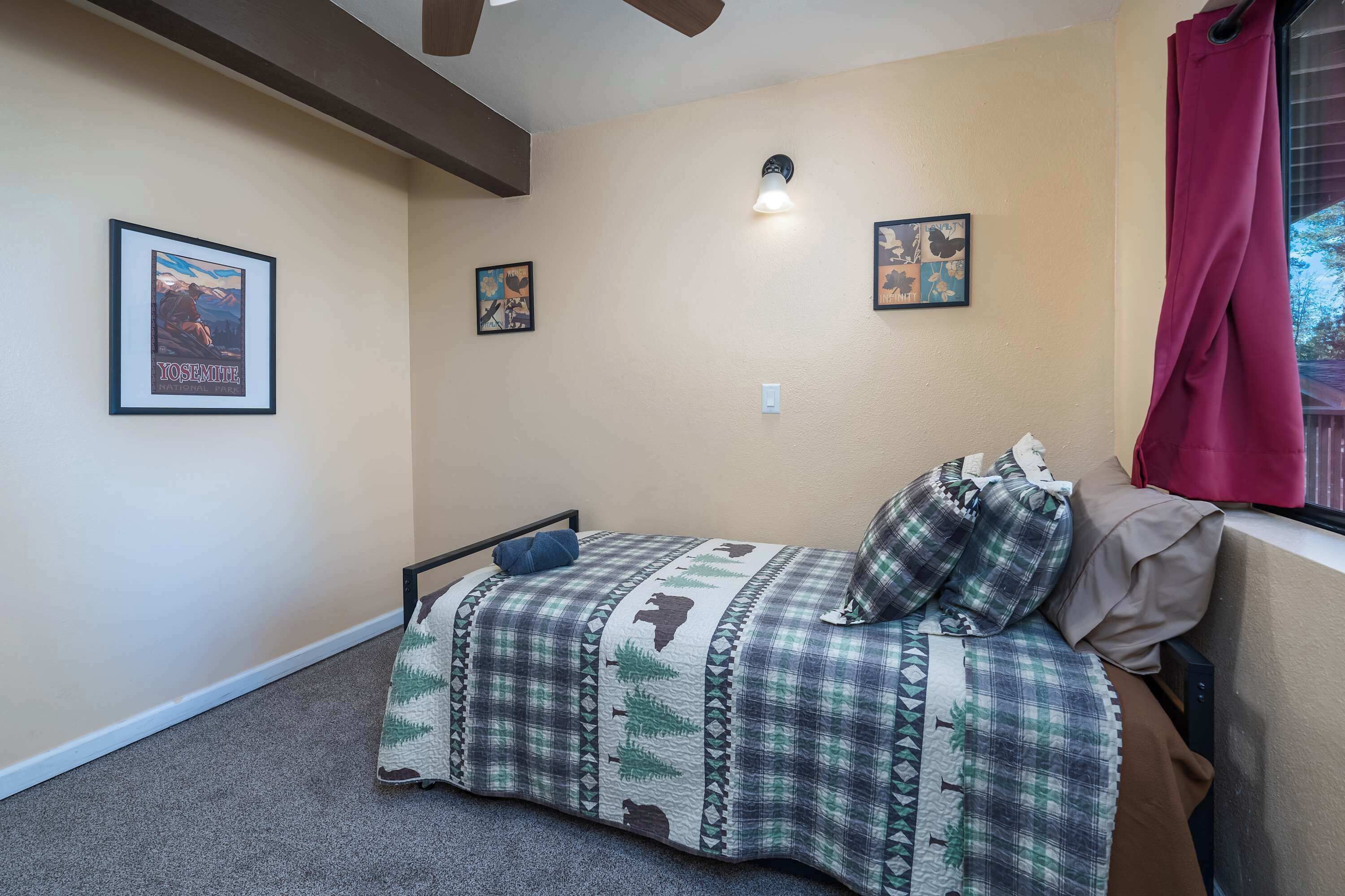 Un dormitorio con cama, ventilador de techo y dos cuadros en la pared.