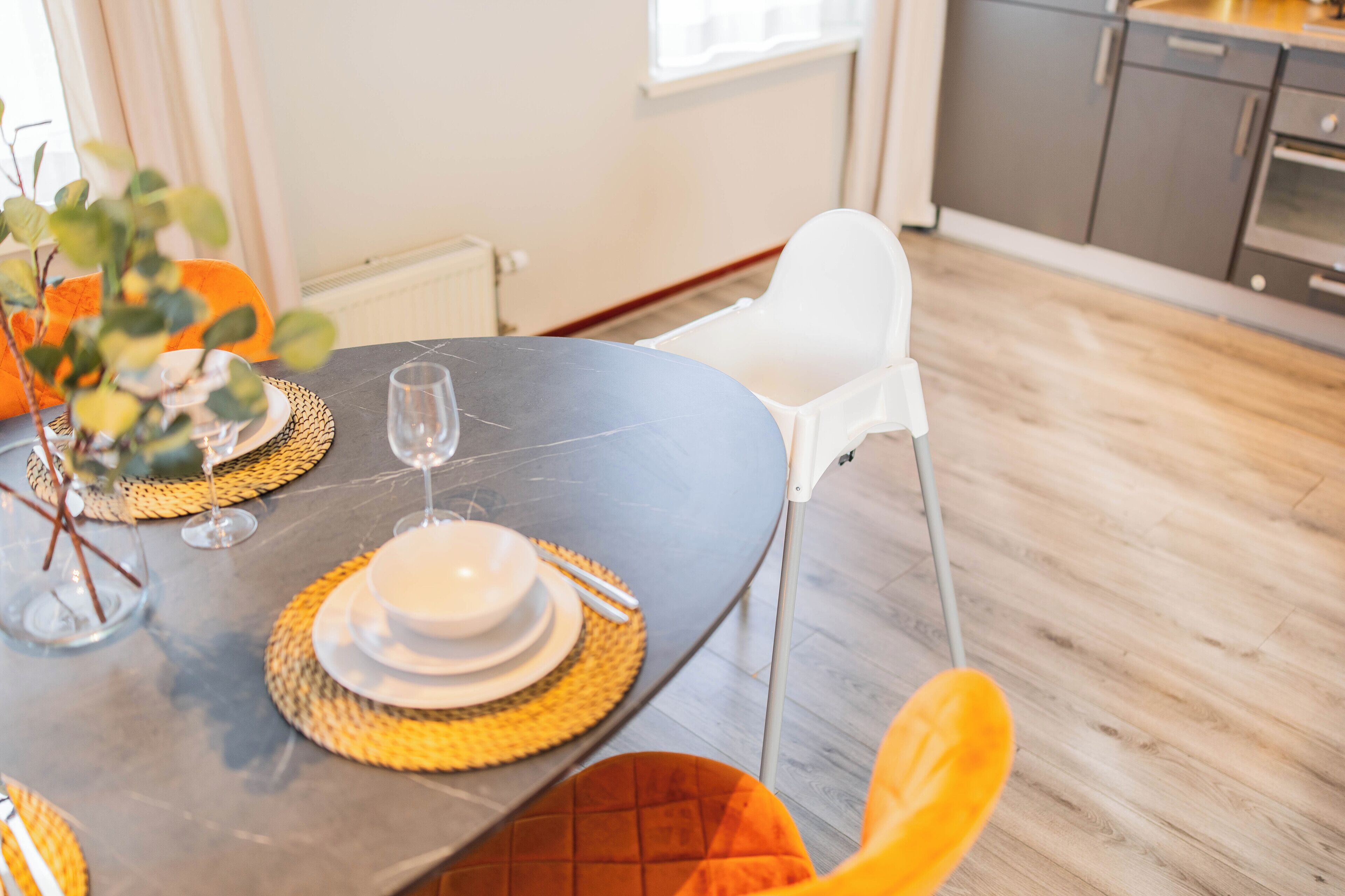 A dining table set with plates, glasses, and a vase of flowers.