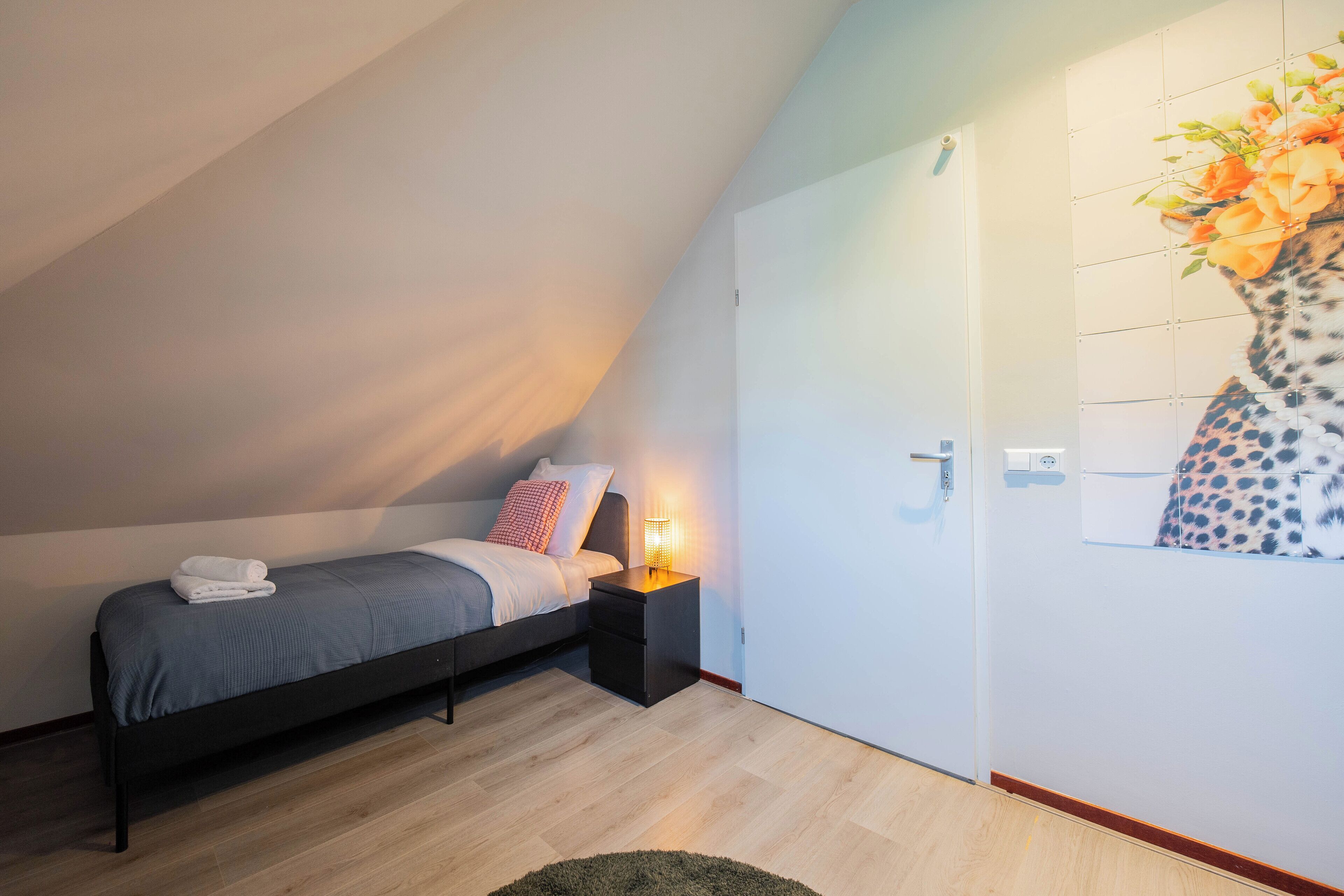 Un dormitorio con cama, mesita de noche y una obra de arte colgada en la pared.