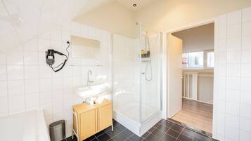 Ein modernes Badezimmer mit einer gläsernen Duschkabine, einem Holzkosmetikschrank und einem weißen Waschbecken.