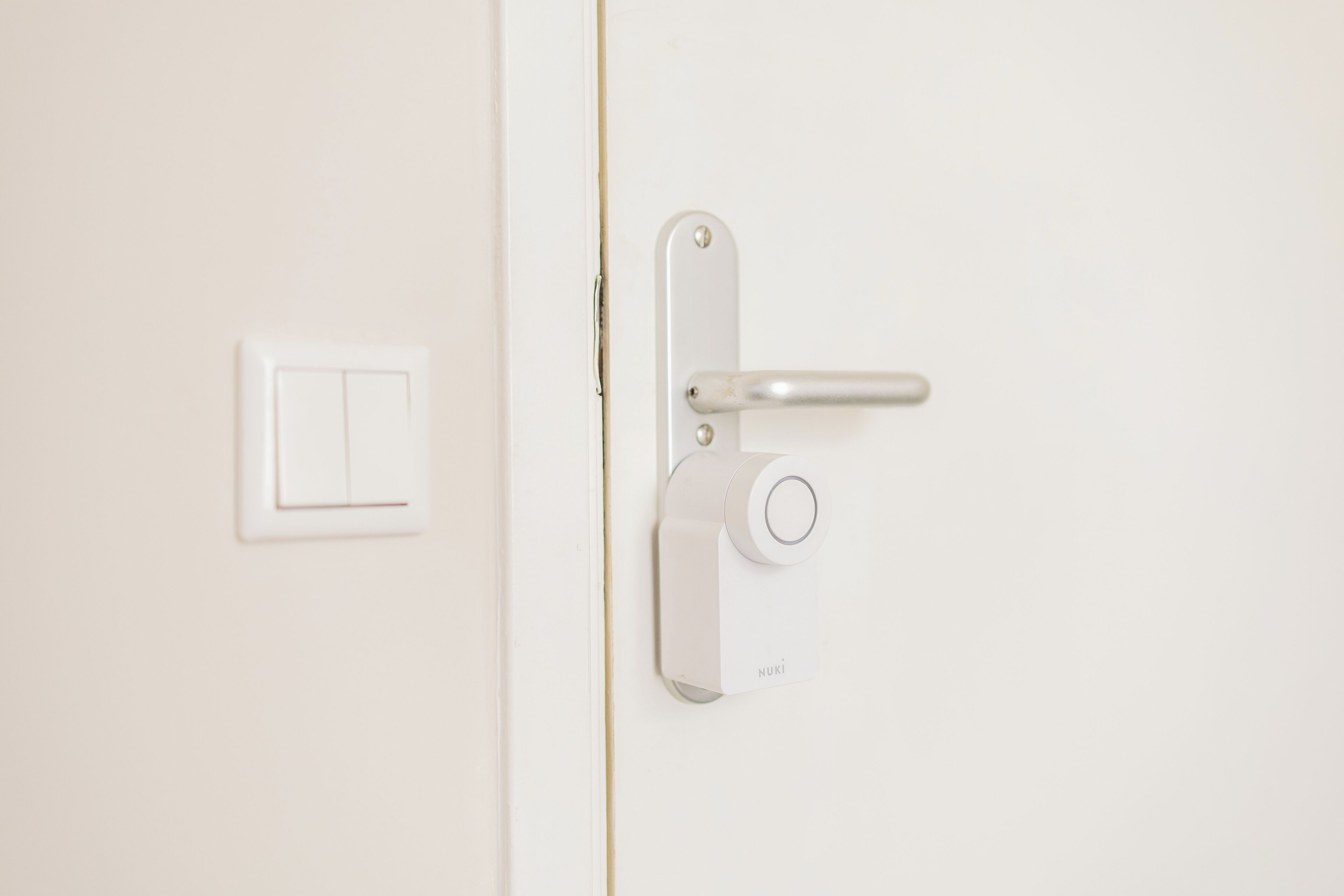 Une porte blanche dotée d’une poignée moderne et d’un interrupteur.