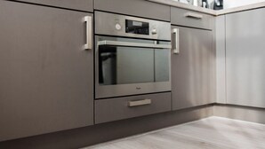 A modern kitchen with stainless steel appliances, a built-in oven, and a countertop with a kettle. - Zwart Janstraat  (Rotterdam)