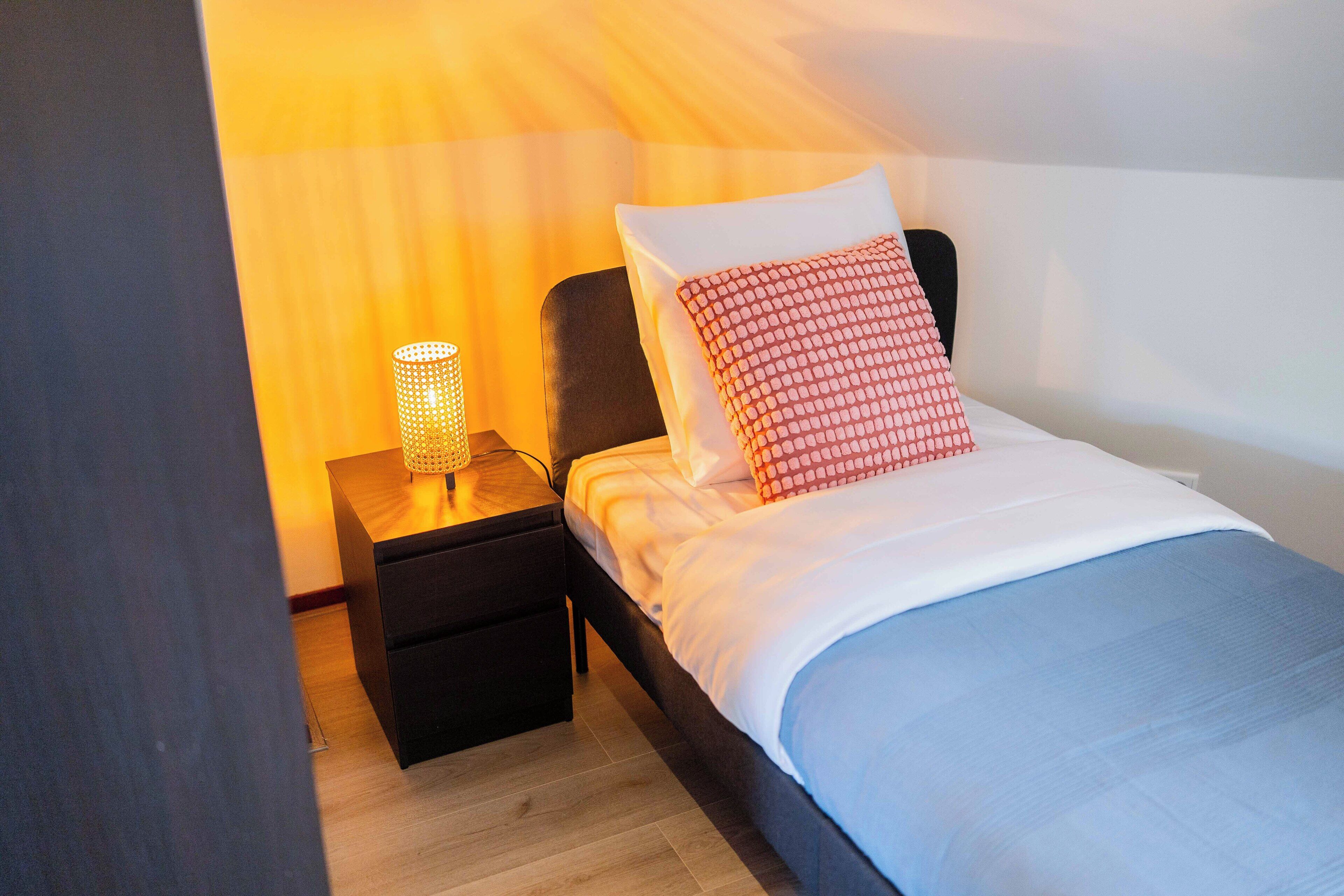 Un dormitorio con cama, mesita de noche y lámpara.