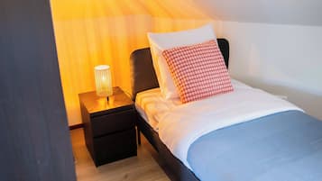 Un dormitorio con cama, mesita de noche y lámpara.
