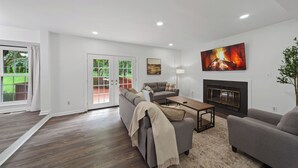 A modern living room with a fireplace, a sofa, a coffee table, and a TV. - Modern and Spacious 4-bedroom house close to DC and National Harbor (Fort Washington)