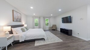 A modern bedroom with a large bed, bedside tables, a TV, and a window with curtains. - Modern and Spacious 4-bedroom house close to DC and National Harbor (Fort Washington)