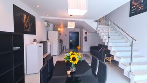 A modern living space with a dining area, kitchen, and staircase.