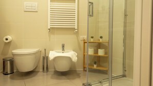 A bathroom with a toilet, bidet, sink, and a glass-enclosed shower.