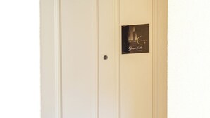A white door with a "Welcome" mat at the bottom and a plaque above the door.