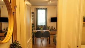 A hallway leading to a dining area with a table, chairs, and a vase of flowers.