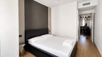 Una camera da letto moderna con un letto grande, una testiera scura e un pavimento in legno.
