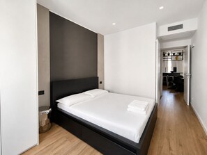 Ein modernes Schlafzimmer mit einem großen Bett, einem dunklen Kopfteil und Holzboden.